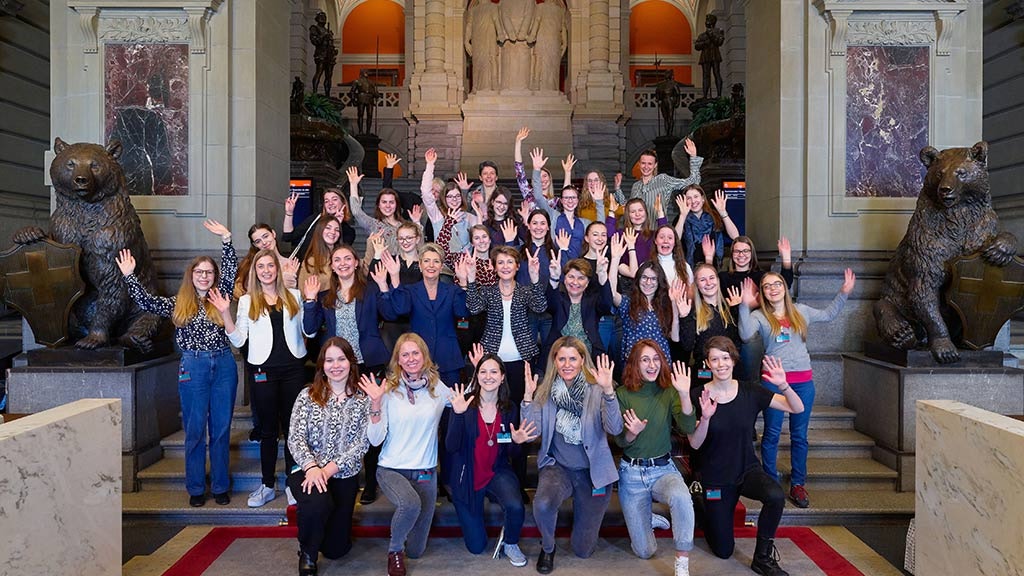 Gruppenbild auf den Treppen des Bundeshauses: die drei amtierenden Bundesrätinnen Karin Keller-Sutter, Simonetta Sommaruga und Viola Amherd mit den 30 jungen Frauen die zum internationalen Frauentag nach Bern eingeladen wurden. Im Hintergrund sind die Statuen der drei Eidgenossen zu sehen.