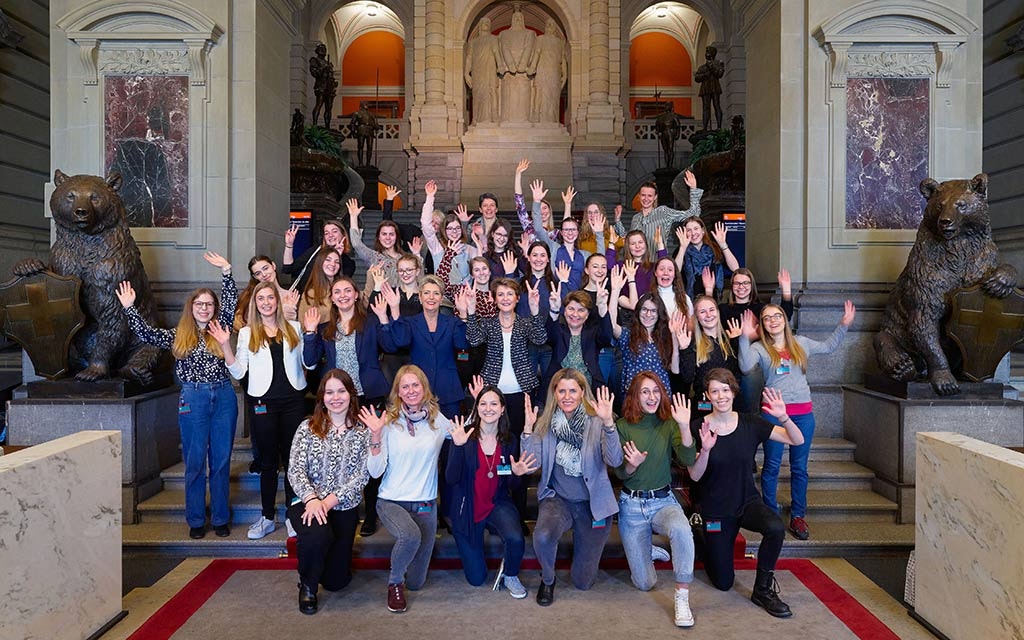 Foto di gruppo sulle scale di Palazzo federale: le tre consigliere federali in carica Karin Keller-Sutter, Simonetta Sommaruga e Viola Amherd con le 30 giovani donne invitate a Berna in occasione della Giornata internazionale delle donne. Sullo sfondo s’intravvedono le statue dei tre confederati.